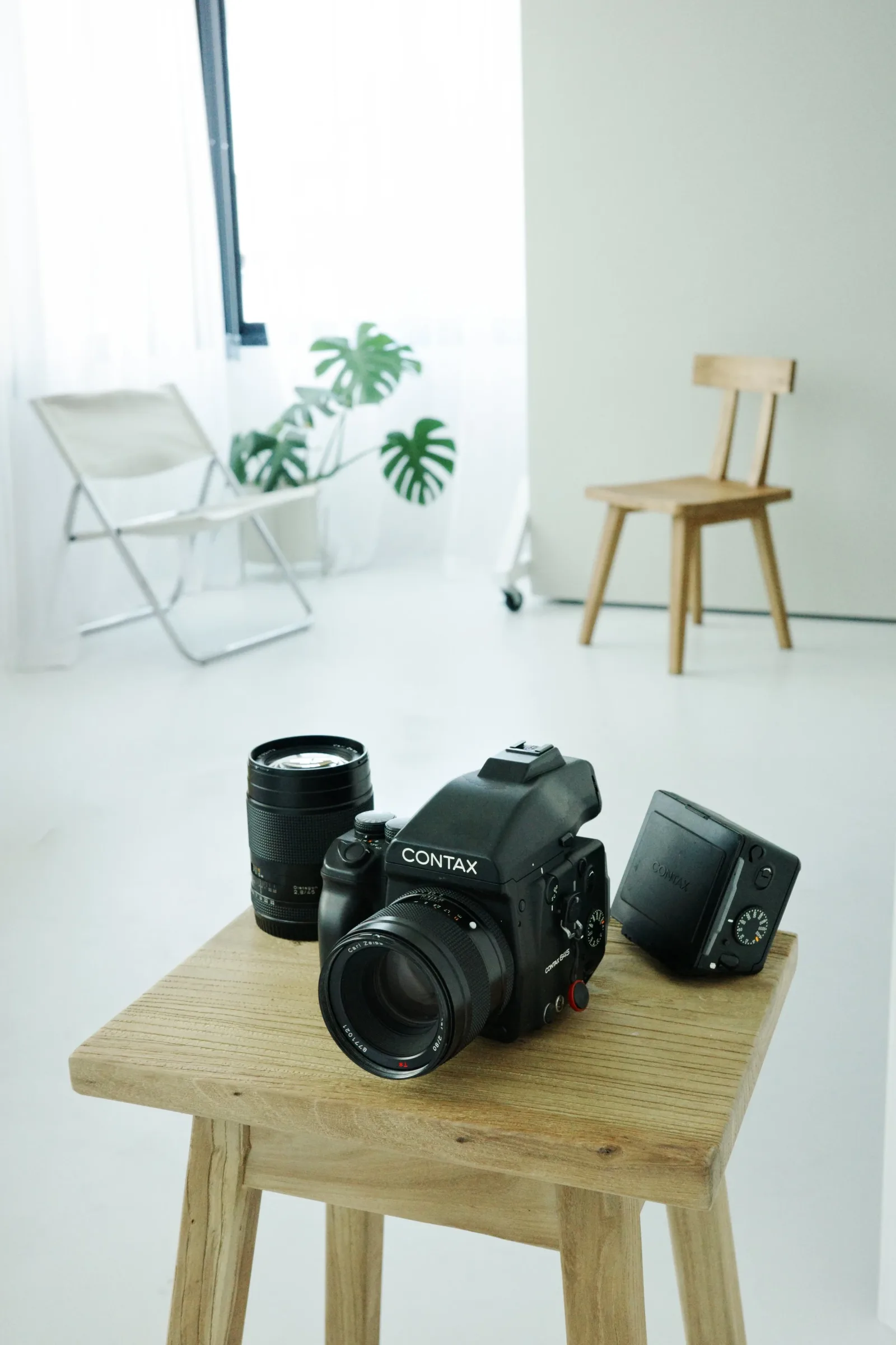 Una Contax 645 con un objetivo extra y un respaldo de película, sobre un banco de madera en el estudio.